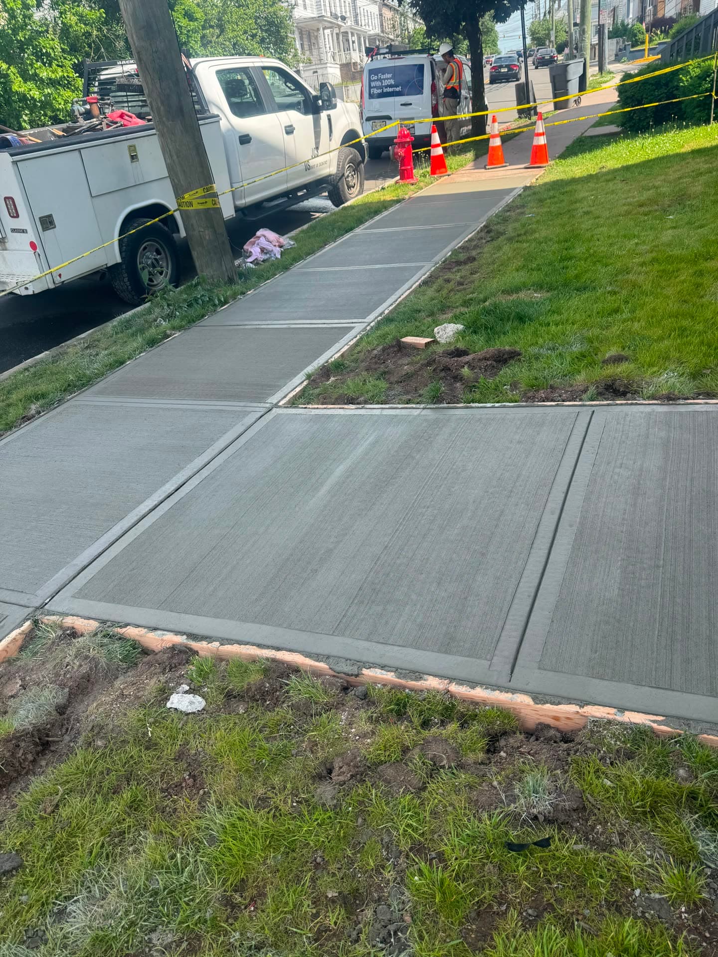 A crew finishing a freshly poured concrete driveway slab with hand trowels on a residential property